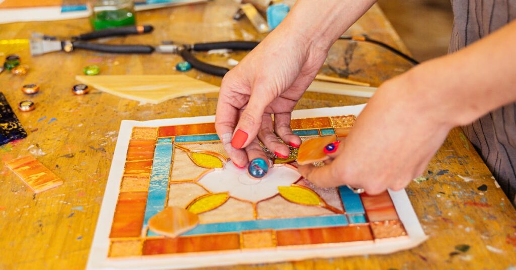 Close-up of artisan creating stained glass piece with colorful tools and materials on work table.
